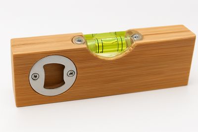 Bamboo bottle opener with spirit level — Durable bamboo bottle opener combining a bubble vial level with engraved text for DIY lovers.