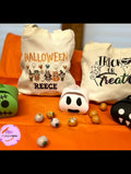 Custom Halloween tote bag with name — Double‑sided Halloween tote bag featuring cartoon costume characters with a personalised name on one side and a “Trick or Treat” design with bats and webs on the reverse.
